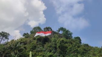 Komunitas Relawan Lampung Bersama TNI Polri Kibarkan Bendera Raksasa di Tebing Spagoh