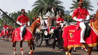 Sejumlah anggota Paspampres mengendarai Kereta Kencana Ki Jaga Raksa yang membawa duplikat Bendera Pusaka Merah Putih dan Teks Proklamsi ketika Parade Kirab Bendera Pusaka dari Monas menuju Istana Merdeka di Jakarta Pusat, Rabu (17/8/2022). [Suara.com/Alfian Winanto]