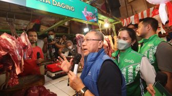 Menteri Perdagangan Zulkifli Hasan didampingi Director of Central Public Affairs at Grab Indonesia Tirza R Munusamy (kedua kiri) berbincang dengan pembeli saat berkunjung di Pasar Tomang Barat, Jakarta, Kamis (18/8/2022).  
