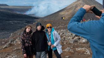 Sejumlah orang berswafoto saat mengunjungi lokasi erupsi Gunung Fagradalsfjall di Grindavik, Islandia, Kamis (4/8/2022). [Haraldur Gudjonsson / AFP]