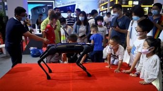 Orang-orang melihat robot berkaki empat pada acara Konferensi Robot Dunia 2022 di Beijing, China, Kamis (18/8/2022). [WANG Zhao/AFP]