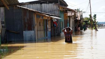 Warga berjalan menerobos banjir di kompleks Kokoda Kota Sorong, Papua Barat, Selasa (23/8/2022). ANTARA FOTO/Olha Mulalinda
