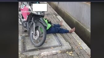 Potret Ojol Terciduk Tidur di Trotoar dengan Posisi Motor Jadi Bantal, Alasannya Bikin Terharu