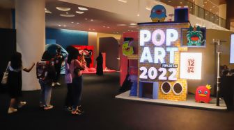 Pengunjung melihat instalasi seni yang dipamerkan pada pameran Pop Art Jakarta di Senayan Park, Jakarta Selatan, Rabu (24/8/2022). [Suara.com/Alfian Winanto]