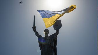 Sebuah drone terbang dengan bendera nasional Ukraina raksasa, melewati monumen Tanah Air saat Hari Kemerdekaan Ukraina, Rabu (24/8/2022). [Dimitar DILKOFF / AFP]
