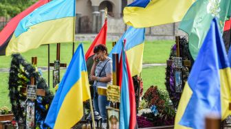 Seorang wanita berdoa selama upacara untuk tentara Ukraina yang gugur di Pemakaman Lychakiv, Lviv, Ukraina, Rabu (24/8/2022). [YURIY DYACHYSHYN / AFP]