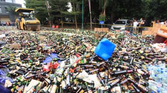 Petugas memusnahkan minuman keras (miras) dengan alat berat ketika rilis hasil Operasi Kamtibmas di Polda Metro Jaya, Jakarta, Jumat (26/8/2022). [ANTARA FOTO/Reno Esnir/foc]
