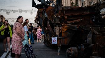 Seorang wanita tua melihat peralatan militer Rusia yang hancur di jalan Khreshchatyk, Kyiv, Ukraina, Minggu (21/8/2022). [Dimitar DILKOFF / AFP]