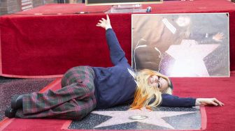 Penyanyi Avril Lavigne berpose di atas bintang barunya di Hollywood o Fame setelah upacara penghargaan untuknya, di Los Angeles, Rabu (31/8).  VALERIE MACON / AFP

