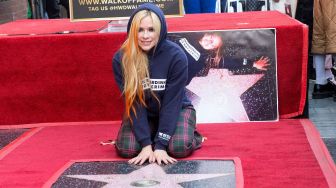 Penyanyi Avril Lavigne berpose di atas bintang barunya di Hollywood o Fame setelah upacara penghargaan untuknya, di Los Angeles, Rabu (31/8).  VALERIE MACON / AFP

