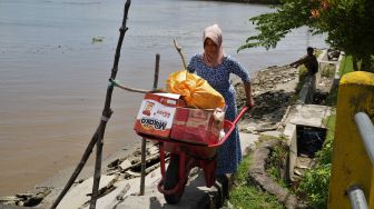 Warga berusaha melewati jalan yang putus akibat abrasi sungai di Desa Muarasampara, Konawe, Sulawesi Tenggara, Kamis (1/9/2022). ANTARA FOTO/Jojon