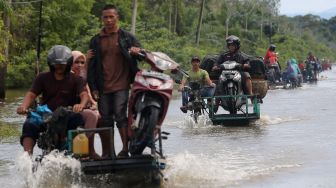 Pengendara memanfaatkan jasa angkut kendaraan roda dua untuk melintasi jalan yang terendam banjir di Desa Layung, Bubon, Aceh Barat, Aceh, Jumat (2/9/2022).  ANTARA FOTO/Syifa Yulinnas
