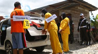 Tiga tersangka melakukan adegan memasukkan tubuh korban Arnold Lokbere ke dalam mobil saat mengikuti rekonstruksi pembunuhan dan mutilasi empat warga di Timika, Papua, Sabtu (3/9/2022). ANTARA FOTO/Sevianto Pakiding
