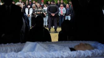 ImaSeorang polisi berjaga saat para pelayat menyaksikan prosesi pemakaman pemimpin terakhir Uni Soviet Mikhail Gorbachev di Pemakaman Novodevichy, Moskow, Rusia Sabtu (3/9/2022). [Alexander ZEMLIANICHENKO / POOL / AFP]