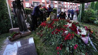 Para pelayat meletakkan bunga di atas makam pemimpin terakhir Uni Soviet Mikhail Gorbachev saat pemakamannya di Pemakaman Novodevichy, Moskow, Rusia Sabtu (3/9/2022). [Alexander ZEMLIANICHENKO / POOL / AFP]