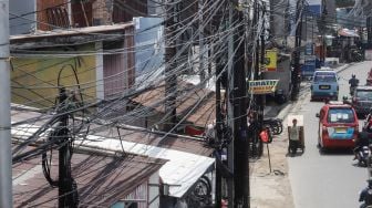 Deretan instalasi kabel yang semrawut di Kramat Jati, Jakarta Timur, Selasa (6/9/2022). [Suara.com/Alfian Winanto]