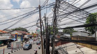 Deretan instalasi kabel yang semrawut di Kramat Jati, Jakarta Timur, Selasa (6/9/2022). [Suara.com/Alfian Winanto]