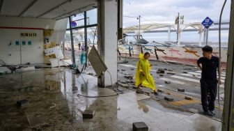 Pejalan kaki melewati deretan toko yang rusak parah akibat Topan Hinnamnor di Busan, Korea Selatan, Selasa (6/9/2022). [Anthony WALLACE/AFP]