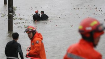 Petugas menyelamatkan seorang pria yang terjebak banjir akibat Topan Hinnamnor di Ulsan, Korea Selatan, Selasa (6/9/2022). [YONHAP/AFP]