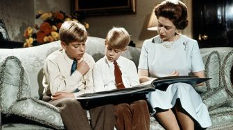 Ratu Elizabeth II, bersama dua putranya Pangeran Andrew (kiri) dan pangeran Edward, membaca sebuah buku di Istana Buckingham selama perekaman pesan Natal Ratu untuk Persemakmuran yang ditayangkan di TV pada hari Natal, Desember 1971. FOTO PERS TENGAH / AFP
