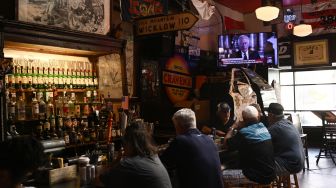 Warga Inggris menyaksikan pidato Raja Inggris Charles III yang disiarkan televisi secara langsung dari Istana Buckingham di sebuah pub di Washington DC, Amerika Serikat, Jumat (9/9/2022). [Brendan SMIALOWSKI / AFP]