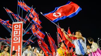 Penampil mengibarkan bendera nasional selama acara peringatan 74 tahun berdirinya negara Korea Utara di Pyongyang, Korea Utara, Jumat (9/9/2022). [KIM Won Jin / AFP]
