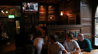 Pengunjung kedai Deacon Brodies Tavern di Edinburgh menonton pidato Raja Inggris Charles III yang disiarkan secara langsung dari Istana Buckingham di Edinburgh, Skotlandia, Jumat (9/9/2022). [Paul ELLIS / AFP]