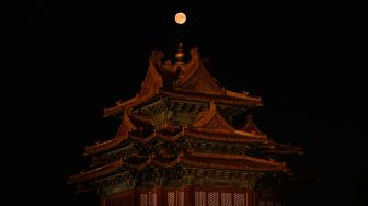 Bulan purnama terlihat di atas menara bersejarah saat Festival Pertengahan Musim Gugur di Beijing, China, Sabtu (10/9/2022). [Jade Gao / AFP]