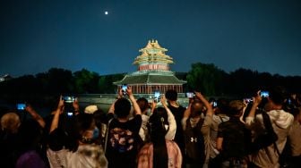 Orang-orang mengambil foto bulan dan menara bersejarah saat Festival Pertengahan Musim Gugur di Beijing, China, Sabtu (10/9/2022). [Jade Gao / AFP]