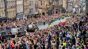 Masyarakat berkumpul di sepanjang Royal Mile untuk menyaksikan mobil jenazah yang membawa peti mati Ratu Elizabeth II menuju Istana Holyroodhouse, Edinburgh, Skotlandia, Minggu (11/9/2022). [Jane Barlow / POOL / AFP]