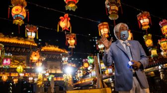 Seorang pria menghadiri pertunjukan lentera saat Festival Pertengahan Musim Gugur di kuil Wong Tai Sin di Hong Kong, China, Kamis (8/9/2022). [ISAAC LAWRENCE / AFP]