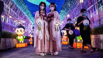 Wanita berkostum menghadiri pertunjukan lentera saat Festival Pertengahan Musim Gugur di kuil Wong Tai Sin di Hong Kong, China, Kamis (8/9/2022). [ISAAC LAWRENCE / AFP]
