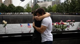 Kerabat para korban yang tewas saling berpelukan saat Peringatan 9/11 di New York, Amerika Serikat, Minggu (11/9/2022). [Yuki IWAMURA / AFP]
