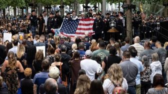 Anggota Departemen Pemadam Kebakaran New York mengibarkan bendera saat Peringatan 9/11 di New York, Amerika Serikat, Minggu (11/9/2022). [Yuki IWAMURA / AFP]