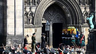 Para prajurit membawa peti mati Ratu Elizabeth II ke dalam Katedral St Giles untuk disemayamkan di Edinburgh, Skotlandia, Senin (12/9/2022). [Paul ELLIS / AFP]