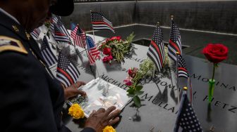 Kolonel Davis menyentuh foto rekannya Kapten Micheal Dermott Mullan yang tewas saat Peringatan 9/11 di New York, Amerika Serikat, Minggu (11/9/2022). [Yuki IWAMURA / AFP]
