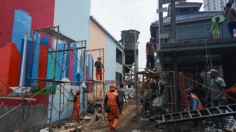 Sejumlah petugas Penanganan Prasarana & Sarana Umum (PPSU) menyelesaikan pembuatan mural di Kampung Gembira Gembrong, Jakarta Timur, Rabu (14/9/2022). [Suara.com/Alfian Winanto]