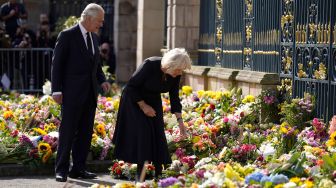 Raja Inggris Charles III dan Permaisuri Camilla melihat karangan bunga yang diberikan masyarakat di luar Kastil Hillsborough, Belfast, Irlandia Utara, Selasa (13/9/2022). [Niall Carson / POOL / AFP]