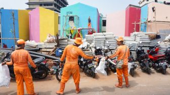 Sejumlah petugas Penanganan Prasarana & Sarana Umum (PPSU) menyelesaikan pembuatan mural di Kampung Gembira Gembrong, Jakarta Timur, Rabu (14/9/2022). [Suara.com/Alfian Winanto]