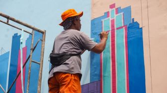 Sejumlah petugas Penanganan Prasarana & Sarana Umum (PPSU) menyelesaikan pembuatan mural di Kampung Gembira Gembrong, Jakarta Timur, Rabu (14/9/2022). [Suara.com/Alfian Winanto]