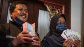 Samin (kiri) beserta istri Sri Kadarwati (kanan) menunjukkan uang baru tahun emisi 2022 usai menukarkan uang rusak miliknya yang dimakan rayap di kantor Perwakilan Bank Indonesia, Solo, Jawa Tengah, Kamis (15/9/2022). [ANTARA FOTO/Mohammad Ayudha/rwa].