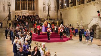 Orang-orang memberikan penghormatan di dekat peti mati mendiang Ratu Elizabeth II, yang terbaring di catafalque di Westminster Hall di Istana Westminster di London, Inggris, Jumat (16/9/2022). [AFP Photo]

