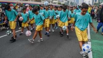 Sejumlah anak bermain bola saat parade perkenalan maskot Piala Dunia U-20 2023 pada Hari Bebas Kendaraan Bermotor atau Car Free Day (CFD) di kawasan Bunderan Hotel Indonesia, Jakarta, Minggu (18/9/2022). [ANTARA FOTO/Galih Pradipta/tom]