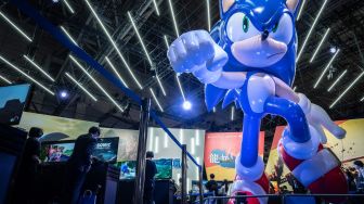 Pengunjung bermain video game disebelah karakter game &#039;Sonic&#039; saat acara Tokyo Game Show di prefektur Chiba, Tokyo, Jepang, Kamis (15/9/2022). [Yuichi YAMAZAKI/AFP]