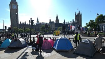 Masyarakat membangun tenda mereka di depan Westminster Hall dan Elizabeth Tower saat mereka mengantri untuk memberi penghormatan kepada mendiang Ratu Elizabeth II yang terbaring di Westminster Hall, London, Inggris, Sabtu (17/9/2022). [JUSTIN TALLIS / AFP]