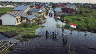 Foto udara sejumlah warga melintasi di permukiman sekitar rumahnya yang terendam banjir di Jalan Anoi Ujung, Palangka Raya, Kalimantan Tengah, Sabtu (17/9/2022). [ANTARA FOTO/Makna Zaezar/aww]