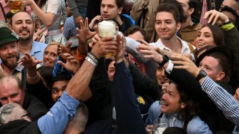 Pengunjung berebut gelas bir saat acara festival bir Oktoberfest di lapangan pameran Theresienwiese di Munich, Jerman, Sabtu (17/9/2022). [Christof STACHE / AFP]