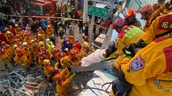 Petugas pemadam kebakaran mengevakuasi seseorang warga dari bangunan runtuh saat operasi penyelamatan akibat gempa bumi di Hualien, Taiwan, Minggu (18/9/2022). [Handout / National Fire Agency / AFP]