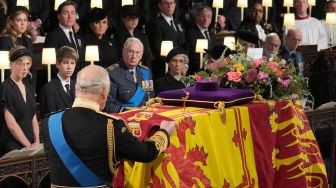 RRaja Charles III menempatkan Queen's Company Camp Color of the Grenadier Guards di atas peti mati saat prosesi pemakaman Ratu Inggris Elizabeth II di Kapel St George yang ada di dalam Kastil Windsor, Inggris, Senin (19/9/2022).  [Jonathan Brady / POOL / AFP]
