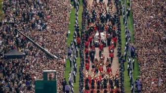 Warga Inggris menyaksikan iring-iringan yang membawa peti mati Ratu elizabeth II saat tiba di Kastil Windsor, Inggris, Senin (19/9/2022). [Aaron Chown / POOL / AFP]
